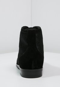 Bottes basses noires en cuir lisse et daim texturé sur le dessus, avec un talon bas en caoutchouc noir massif.