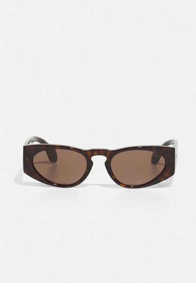 Ochelari de soare din scoică cu lentile maronii, formă unghiulară de cat-eye și rame groase. Prezintă o mică decupare între lentile și sprijinul pentru urechi.