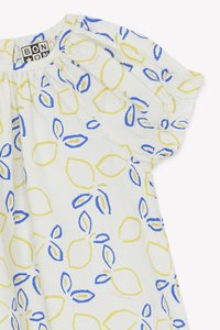 White dress with yellow and blue leaf pattern. Elasticated cap sleeves and gathered neckline. Lightweight, patterned cotton fabric.