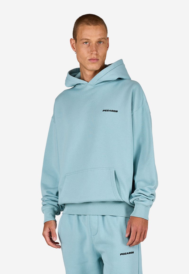 Svetlomodrá mikina s kapucňou, predným vreckom, rebrovanými manžetami a lemom; na hrudi má malý čierny nápis "PEGADOR".