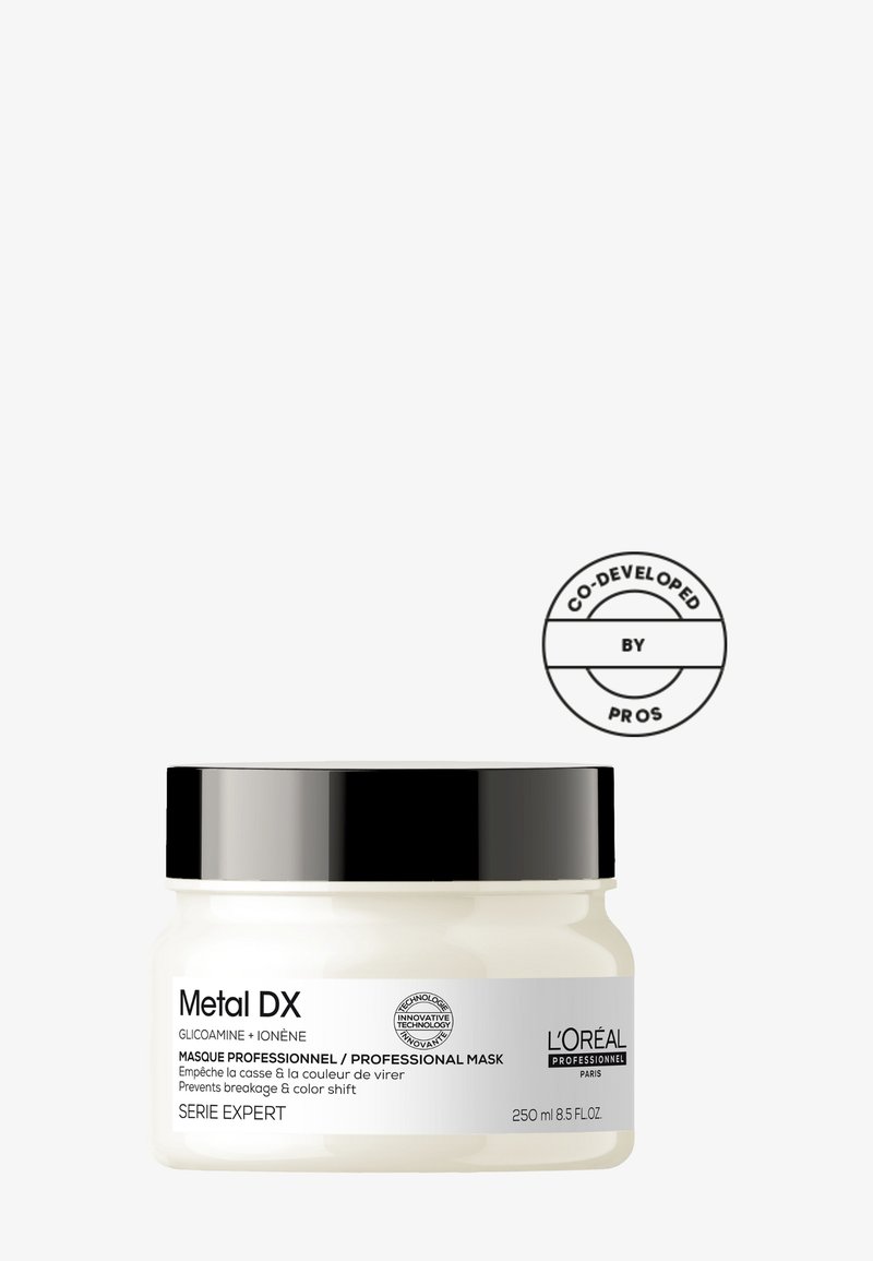 Hvit krukke med svart lokk, merket "Metal DX" i svart tekst, inneholder 250 ml. Har et sirkulært "Co-developed by Pros"-logo.
