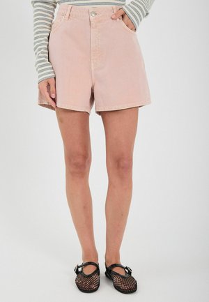 Rosa denimshorts med høj talje, med forlommer og en frayed kant. Sammen med sorte mesh-sko og en stribet langærmet top.