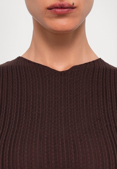 Brown textured top with a ribbed pattern, featuring a V-neckline and a close fit. The fabric has a smooth, slightly glossy finish.