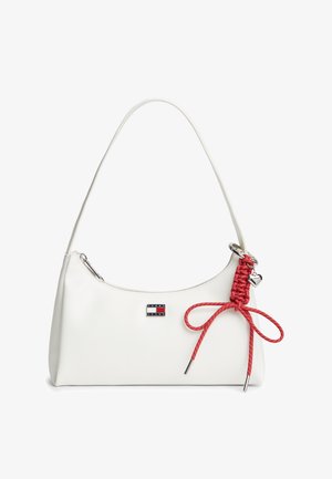 Λευκή τσάντα χειρός με έναν λουρί, λογότυπο Tommy Jeans και κόκκινο πλεκτό κορδόνι με φιόγκο και ασημένιο γοητευτικό καρδιά που κρέμεται στο πλάι.