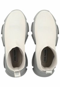 Witte gebreide instapschoenen met een geribbelde textuur, grijze rubberen outsole, zachte kraag en logodetail op de achterkant van de hak.