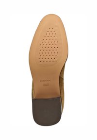 Suela de zapato de ante beige con goma texturizada para mayor adherencia. Nombre de la marca "GEOX" y "PATENTE ITALIANA" grabados en la parte inferior. Forma redondeada.