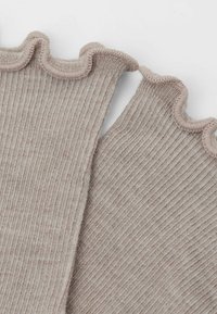 Ribbet, lys beige stof med en b�ølget kant. Tekstureret overflade og subtile striber. Kanterne har et scallop-design. Velegnet til lagdelt påklædning.