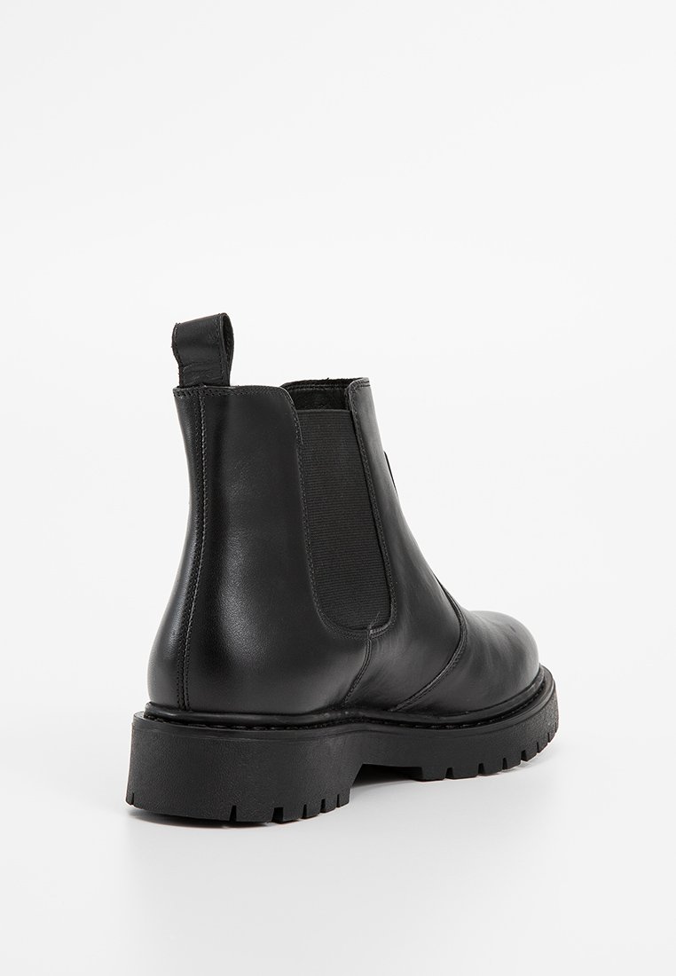 Bottines Chelsea en cuir noir avec panneaux élastiques sur les côtés, une languette de tirage et une semelle en caoutchouc épaisse avec un motif de traction. Fini lisse et élégant.