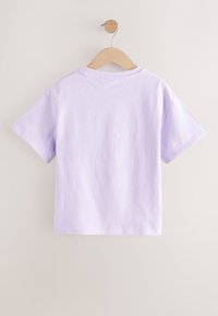 Fliederfarbenes T-Shirt mit kurzen Ärmeln, aufgehängt an einem Holzkleiderbügel, mit Rundhalsausschnitt und glatter, weicher Textur.