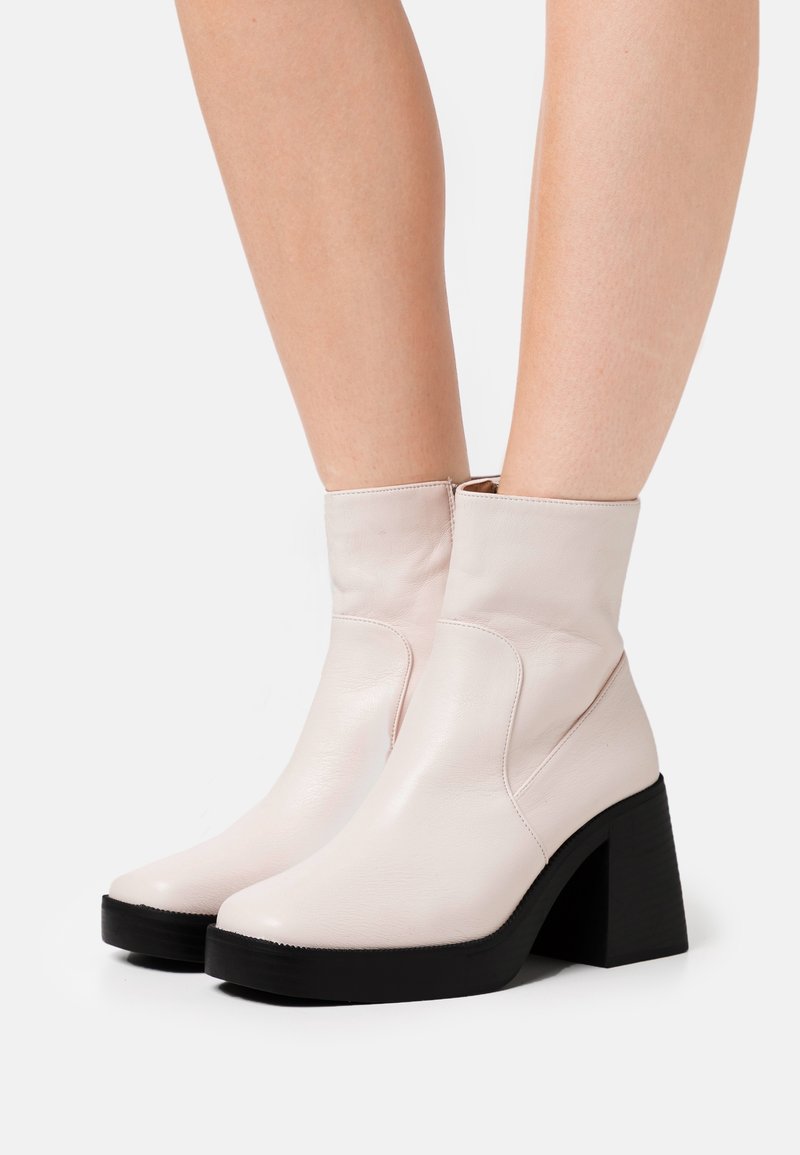 Light pink leather ankle boots with a rounded toe, elastic side panels, and a chunky black heel. Smooth texture with minimal detailing.