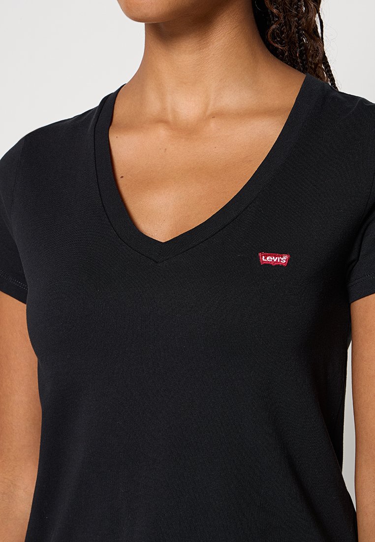 T-shirt en coton noir avec un design en V. Présente un petit logo rouge Levi's sur la poitrine. Texture douce et lisse, coupe ajustée.