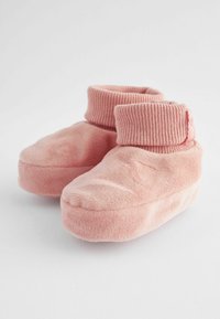 Pehmeät vaaleanpunaiset tossut, jotka on valmistettu pehmeästä materiaalista. Tossuissa on ribby neulekaitale lämpöä ja turvallista istuvuutta varten, pyöristetyt varvastilat ja litteä pohja.