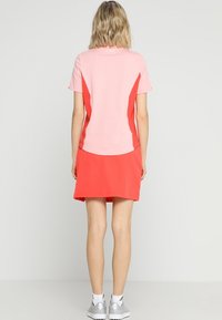 Sukienka polo z różowym gorsetem i intensywnie koralową spódnicą, wykonana z gładkiego materiału, z krótkimi rękawami i sportowymi akcentami.