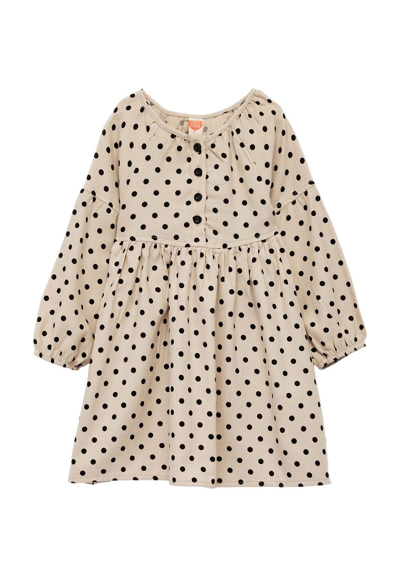 Beige mekko, jossa on mustia pilkkuja, pyöreä pääntie, täysipitkät hihat ja kootut vyötärölinja, jossa on nappisuljenta edessä. Pehmeä kankaan rakenne.