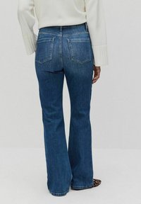 Siniset leveälahkeiset farkut keskipitkä vyötärö, viisi taskua ja haalistunut pesu. Kangas on denimi, jolla on sileä rakenne.