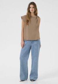 Top marron fără mâneci, cu detaliu nod lateral, asortat cu pantaloni largi de culoare albastră deschisă, cu dungi verticale și un finisaj texturat.