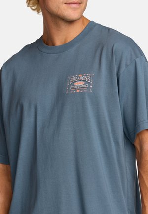 Blue cotton t-shirt with short sleeves and a relaxed fit. Features a graphic logo on the chest in a contrasting color.