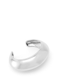 Bracelet en métal argenté avec une surface lisse et polie, présentant un design arrondi et ouvert sans embellissements supplémentaires.