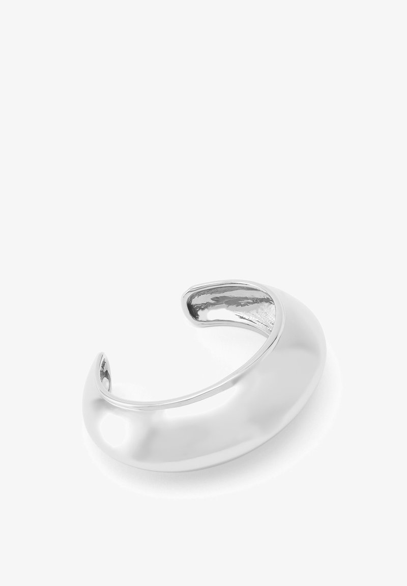 Bracelet en métal argenté avec une surface lisse et polie, présentant un design arrondi et ouvert sans embellissements supplémentaires.