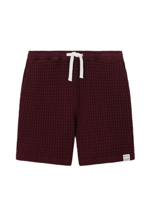 Shorts texturés rouge foncé avec taille élastique et cordon blanc, avec une petite étiquette blanche en bas à droite de l'ourlet.