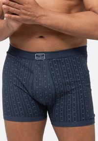 Pantaloni boxer blu navy con un motivo testurizzato e piccoli punti azzurri; vita elasticizzata con etichetta del marchio sul davanti.