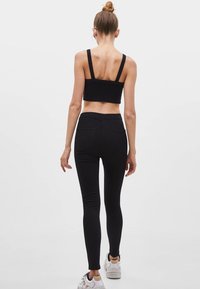 Černé přiléhavé legíny z elastické látky s vysokým pasem a zadními kapsami, doplněné o sladěný černý crop top.