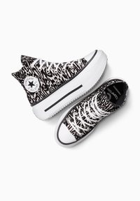 Zapatillas de caña alta y baja con un patrón en blanco y negro, con cordones blancos, puntera redonda y suela de goma que presenta una franja texturizada y un parche con el logo.