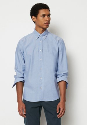 Light blue button-up shirt made from a soft fabric, featuring long sleeves rolled up, a classic collar, and a small embroidered logo.