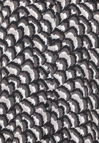 Tissu à motif abstrait de coquilles en noir, blanc et gris avec une rangée verticale de boutons noirs, gros plan sur le textile.