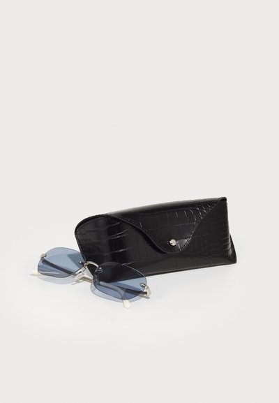 Un toc pentru ochelari de soare negru cu model de crocodil, prevăzut cu închidere tip snap, care conține ochelari de soare cu lentile nuanțate de albastru, cu accesorii din silver și accente din acetat transparent.
