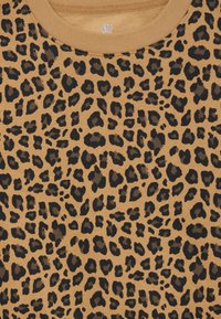 Maglione con motivo leopardato in tessuto color beige. Presenta macchie nere e marroni scure. Collo rotondo con bordino a costine. Texture morbida.