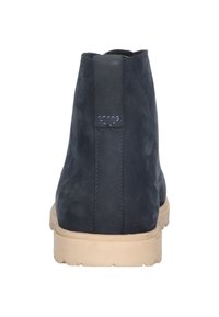 Mörkblå ank stövlar för män med en slät yta, med en kontrasterande beige sula, sömnadsdetaljer och en dragflik baktill.