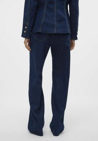 Temno jeans z razširjenimi hlačnicami, z gladko teksturo, petimi žepi in kontrastnimi šivi.