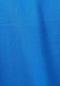 Gros plan d'un tissu bleu texturé avec des motifs de tissage visibles et des ombres subtiles montrant des plis de tissu.