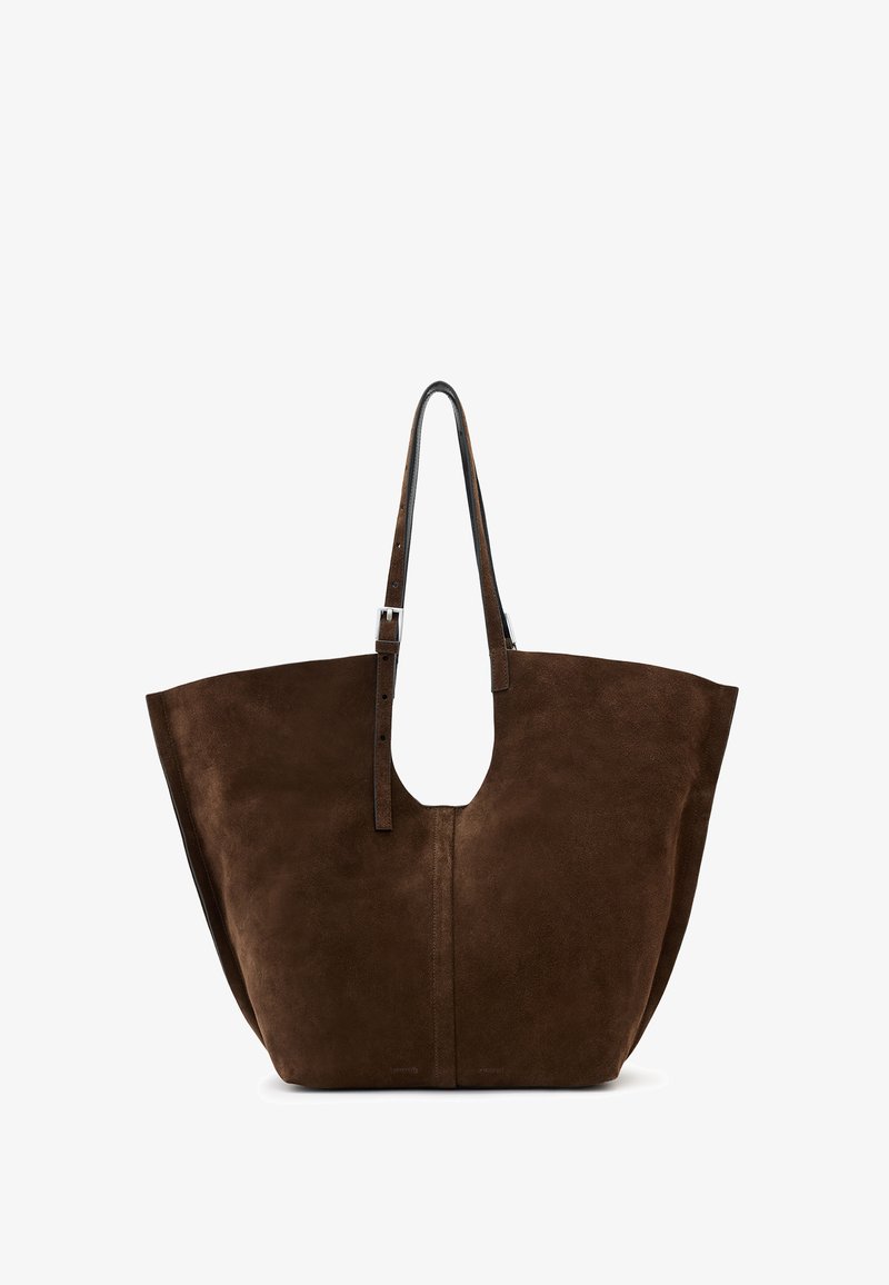 Sac fourre-tout en suede marron avec un corps large, une ouverture sur le dessus et un design simple, doté de longues sangles en cuir et d'un détail de poignée découpé.