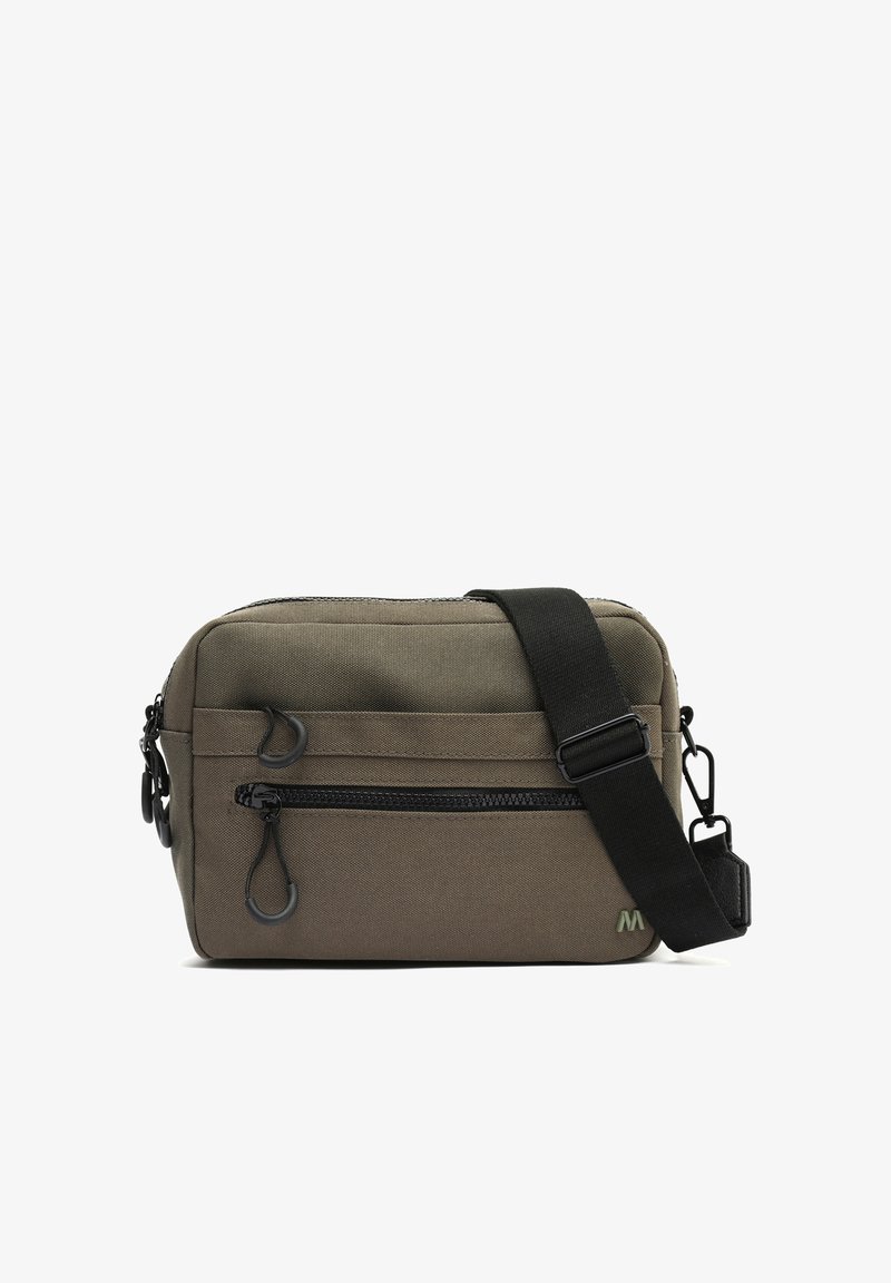 Sac bandoulière compact vert olive avec sangle noire réglable, poche zippée à l'avant et petit détail logo dans le coin inférieur droit.