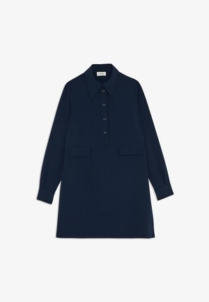 Námořnické modré šaty košilového typu, vyrobené z hladké látky, mají špičatý límec, zapínání na knoflíky vpředu, dvě přední kapsy a dlouhé rukávy s manžetami na knoflíky.