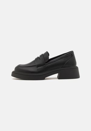 Sorte loafers med en glat læderstruktur, der har en kraftig hæl, bølgede detaljer ved overdelen og minimalistiske designelementer.
