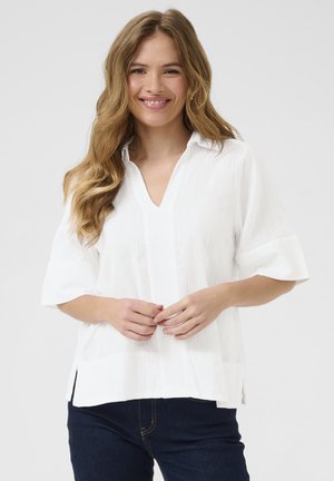Witte shirt met een kraag, korte mouwen, verticale textuur en zijsplitten. Draag het met donkerblauwe jeans.