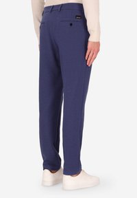 Pantaloni della tuta blu navy realizzati in morbido tessuto, con una vestibilità su misura, due tasche posteriori con chiusura a bottone e una discreta etichetta del marchio.
