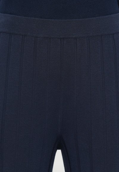 Leggings malha canelada em azul-marinho com uma cintura larga e textura de risca vertical, proporcionando uma silhueta ajustada.