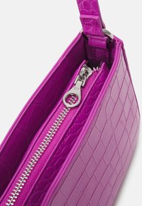 Sac à main violet avec un motif crocodile, doté d'une fermeture éclair et d'une bandoulière en argent, montrant un gros plan du dessus et du compartiment zippé.