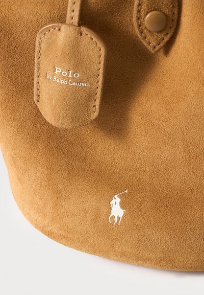 Καφέ τμήμα τσάντας από σουέντ με ετικέτα Polo by Ralph Lauren και λευκό λογότυπο παίκτη πόλο πάνω σε άλογο.