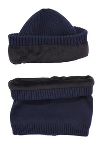 Cappello lavorato a maglia blu navy con design a costine, dotato di un risvolto in pelliccia sintetica nera. Texture morbida con una forma superiore rotonda. Include una sciarpa coordinata.