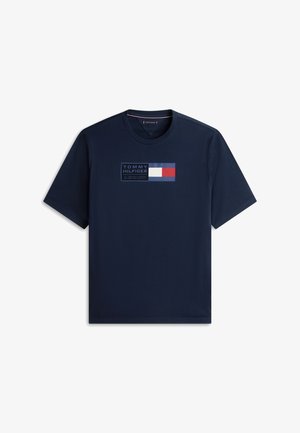 Temno modra majica s kratkimi rokavi in logotipom Tommy Hilfiger ter grafiko rdeče, bele in modre zastave na sredini prsnega koša.