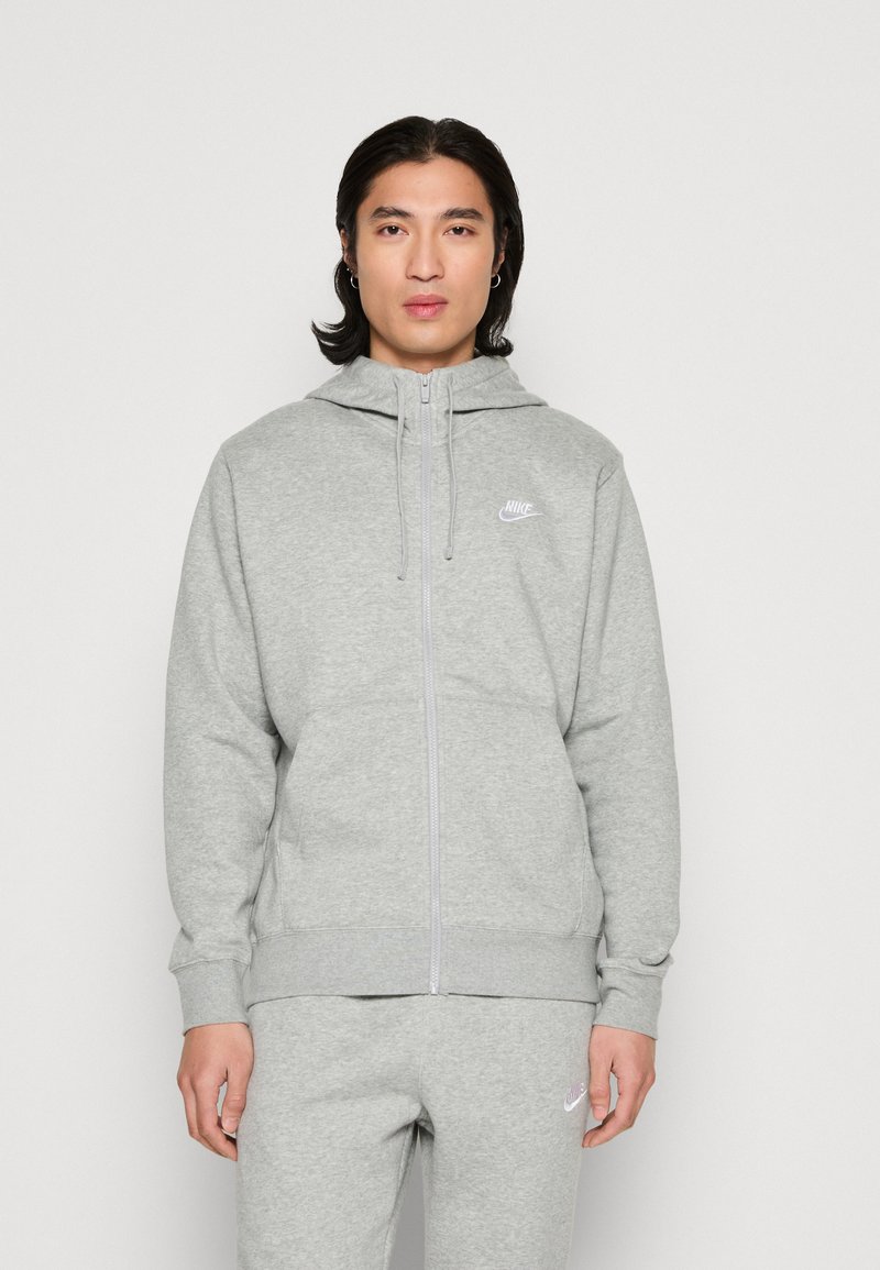 Grauer Sweatshirt mit Reißverschluss und Kapuze. Hergestellt aus weichem Material, mit einem kleinen weißen Nike-Logo auf der Brust. Gerippte Bündchen und Saum.