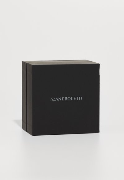 Cutie neagră cu un finisaj mat, având un logo argintiu, colțuri accentuate de un design pliat, cu o apariție minimalistică și elegantă.