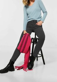 Svartvita mönstrade byxor, ljusblå långärmad topp och en rosa randig scarf, i kombination med svarta ankelboots.