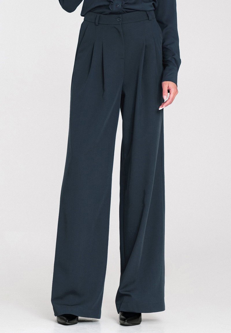 Ciemnoniebieskie spodnie o szerokich nogawkach z wysokim stanem, z plisami z przodu, gładką fakturą i zapięciem na guzik w pasie.