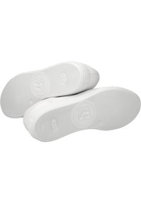 White rubber sneaker soles with textured grip, featuring circular logo and flat heel. Smooth surface with minimal detailing and no patterns.